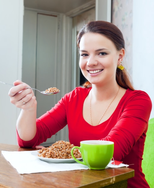 Fille heureuse en rouge mange du sarrasin