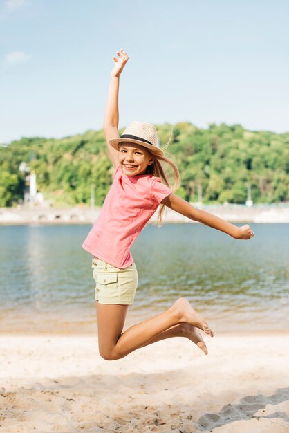 Fille heureuse sautant sur le sable