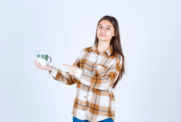 fille heureuse avec une tasse de café debout sur un mur blanc.