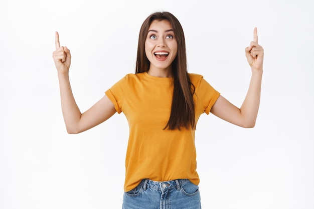 Une fille idiote heureuse et heureuse assiste à un événement amusant ou à une fête d'halloween aime regarder des feux d'artifice pointer les doigts vers le haut en regardant la meilleure publicité avec admiration et joie fond blanc