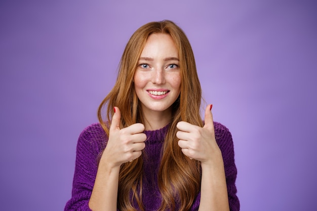 Fille impressionnée admirant le bon goût musical d'un ami montrant les pouces vers le haut et souriant excité et étonné exprimant des commentaires positifs et positifs, approuvant et soutenant le plan sur fond violet.