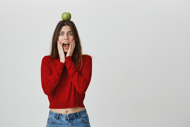 Fille inquiète effrayante tenant la pomme sur la tête comme une cible d'archer