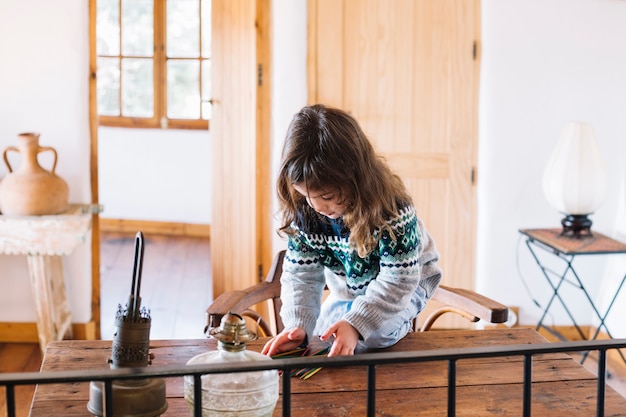 Fille jouant avec des bâtons en plastique sur un bureau en bois