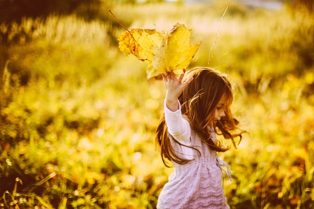 Photo gratuite fille joue avec des feuilles tombées dans la soirée