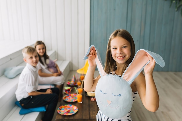 Fille joyeuse montrant le coussin de lapin