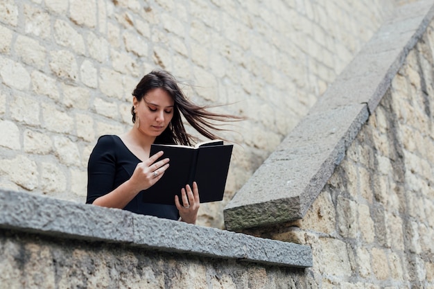 Photo gratuite fille lisant un livre dans une journée venteuse