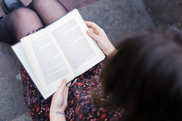 Photo gratuite fille lisant un livre dans la rue