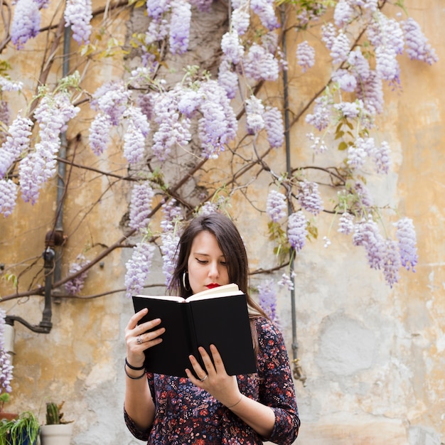 Photo gratuite fille lisant un livre dans la rue