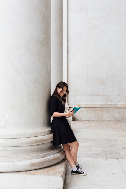 Photo gratuite fille lisant un livre dans la rue