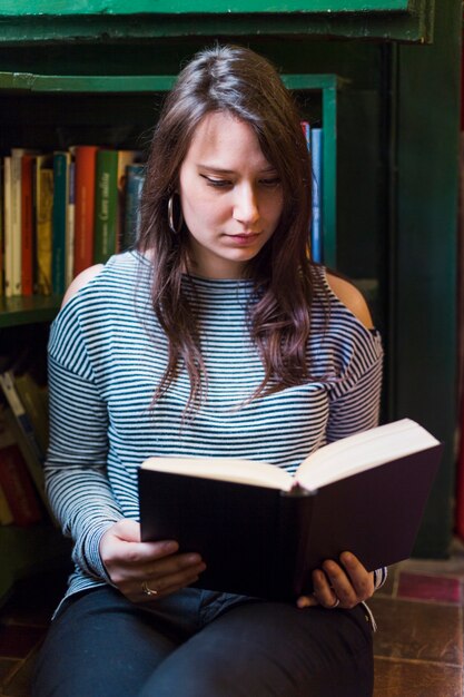 Fille lisant un livre à la maison