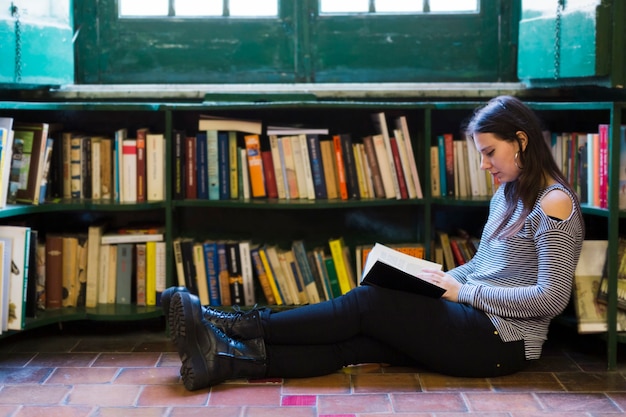 Fille lisant un livre par terre