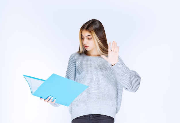 Photo gratuite fille lisant les rapports sur le dossier bleu et faisant des remarques.