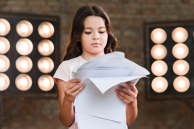 Fille lisant des scénarios devant la lumière de la scène