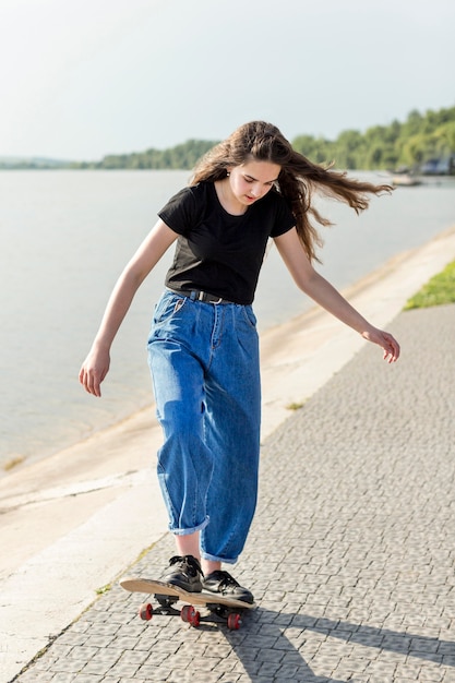 Fille de longue séance sur la planche à roulettes à l'extérieur