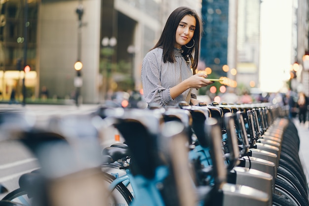 Photo gratuite fille louant un vélo de ville sur un support à vélo