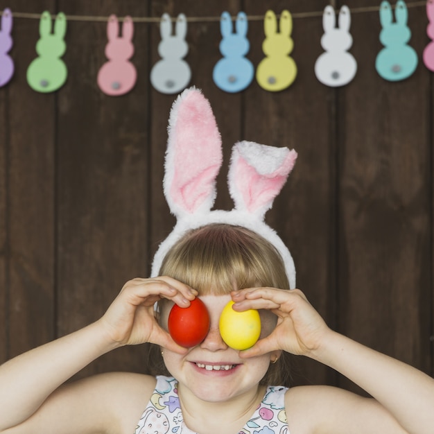 Photo gratuite fille ludique posant avec des oeufs colorés