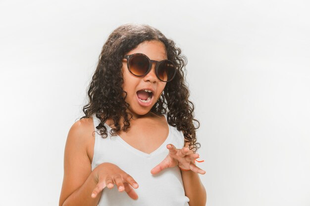 Fille à lunettes de soleil essayant d&#39;effrayer sur fond blanc