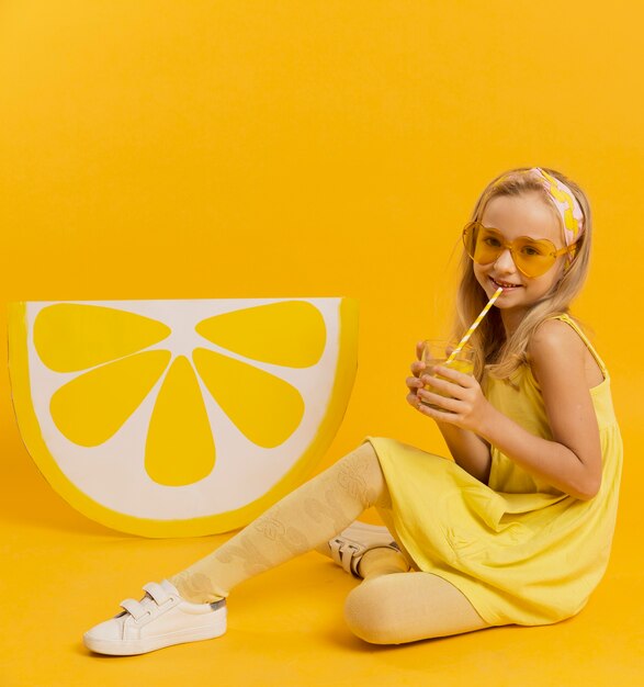 Fille avec des lunettes de soleil posant avec une décoration de tranche de citron