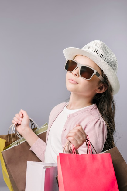 Fille à lunettes de soleil posant avec des sacs à provisions