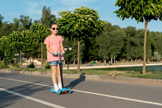 Fille avec des lunettes de soleil trottinette