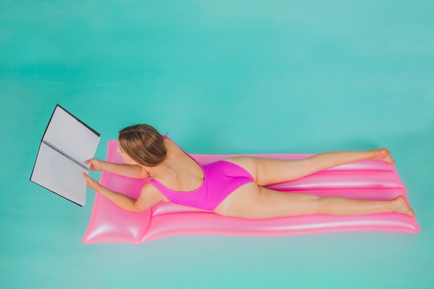 Fille en maillot de bain rose avec dossier sur matelas de billard