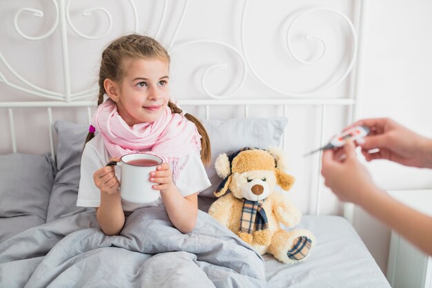 Fille malade utilisant un thermomètre