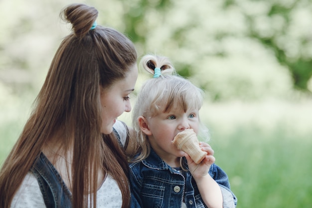 Fille de manger une crème glacée pendant que sa mère la regarde et sourit