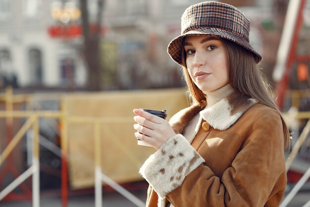 Fille marchant dans une ville de printemps et prenant du café