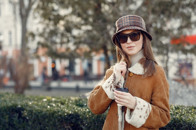 Fille marchant dans une ville de printemps et prenant du café