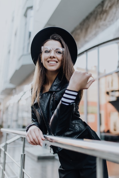 Fille marche dans la ville après la pluie près de vitrines brillantes par temps froid dans la journée