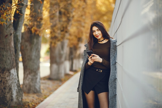 Fille marche. Femme dans un manteau. Dame utilise un téléphone portable.