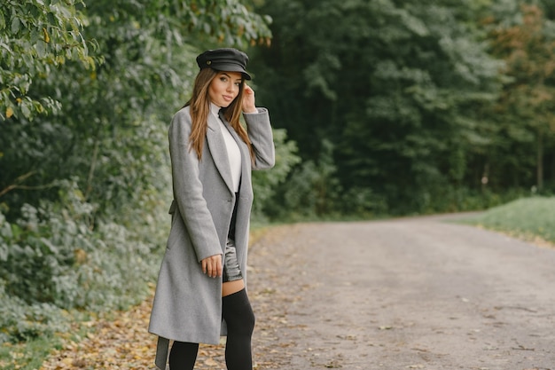 Fille marche. Femme en manteau gris. Brunette avec un bonnet noir.