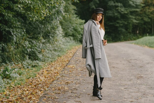 Fille marche. Femme en manteau gris. Brunette avec un bonnet noir.