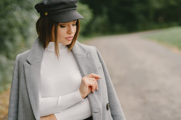 Fille marche. Femme en manteau gris. Brunette avec un bonnet noir.