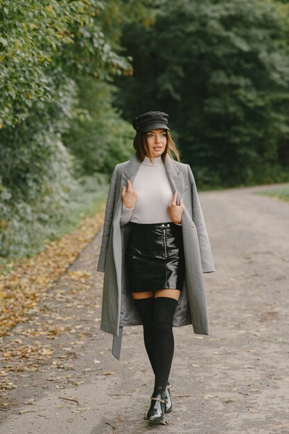 Fille marche. Femme en manteau gris. Brunette avec un bonnet noir.