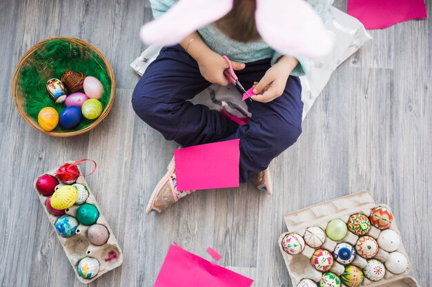 Fille méconnaissable découpant le papier sur le plancher