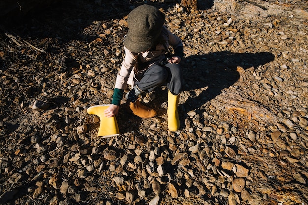 Fille mettant des bottes en caoutchouc