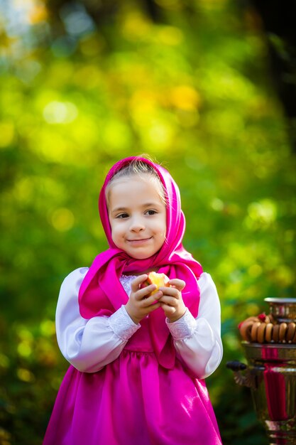 Fille mignonne d'enfant dans un châle et une robe roses, une veste blanche comme Masha et l'ours du dessin animé.