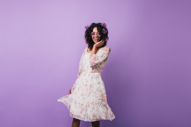 Fille mince avec des alliums dans les cheveux danse heureuse. Agréable jeune femme africaine en robe vintage posant.