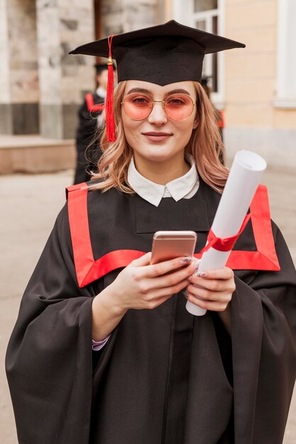 Fille avec mobile à l'obtention du diplôme