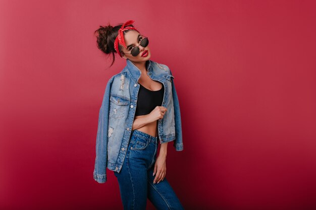 Fille à la mode sérieuse en tenue de denim debout dans une pose confiante