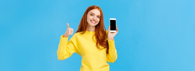 Fille montrant une bonne application recommande de télécharger une application très utile jolie femme rousse en sueur jaune