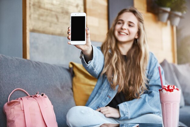 Photo gratuite fille montrant des photos de nouvel appartement tirant fièrement la main wi