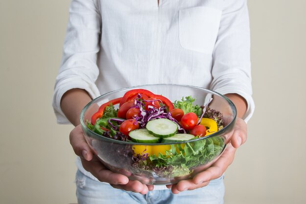 Fille montrant sa salade avec des tomates cerises et des concombres