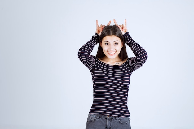 Fille montrant un signe d'oreille de lapin ou de loup.