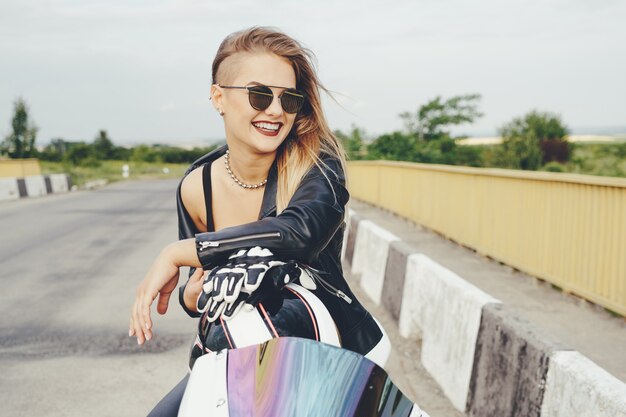 Fille de motard dans un vêtement en cuir sur une moto