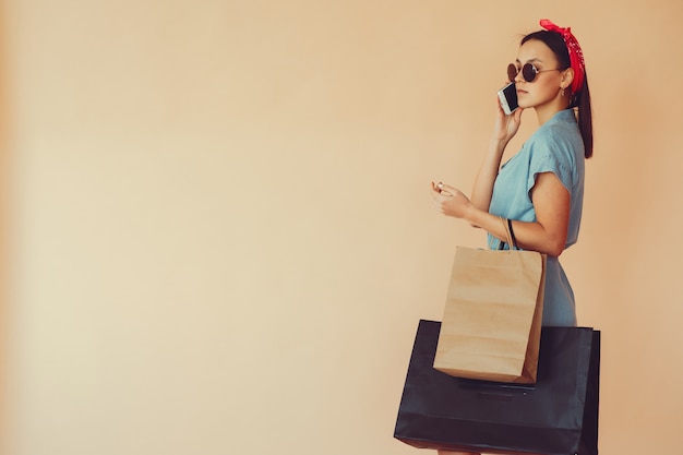 Fille sur un mur jaune avec des sacs à provisions