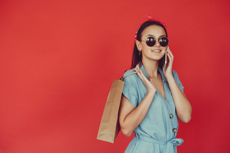 Photo gratuit fille sur un mur rouge avec des sacs à provisions