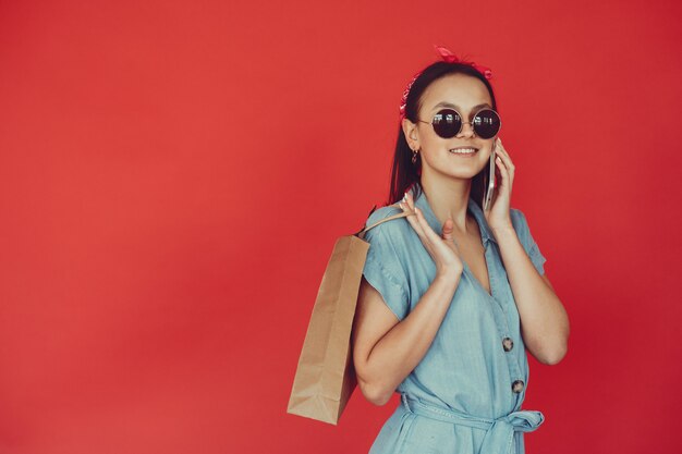 Fille sur un mur rouge avec des sacs à provisions