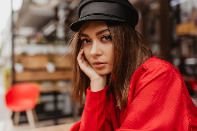 Une fille mystérieuse dans un chemisier en satin spectaculaire touche son visage. Dame aux cils luxuriants luxueux pose pour portrait en gros plan